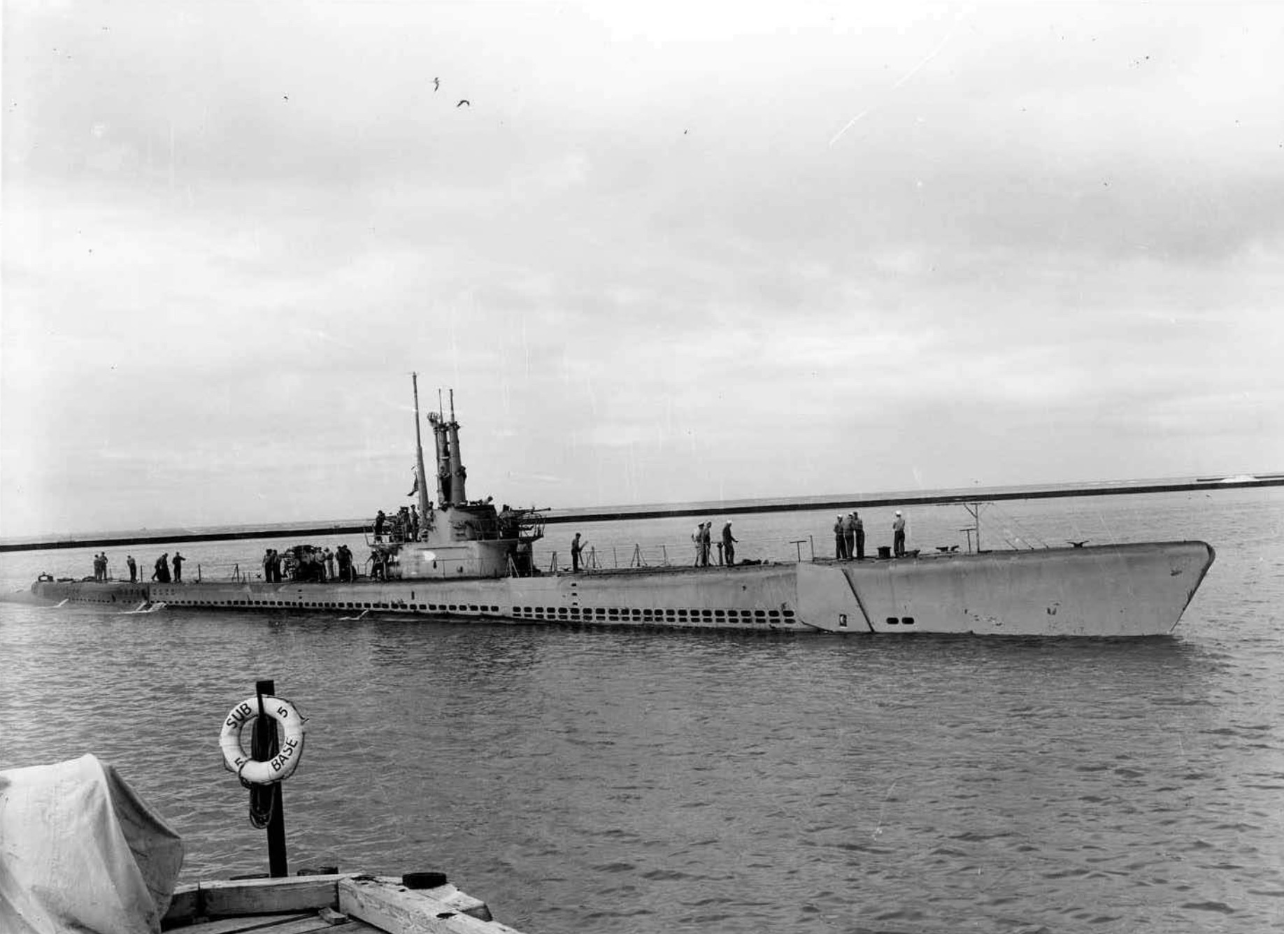 USS Apogon’s officers and crew alongside the conning tower as she heads towards dock at Submarine Base 5. 